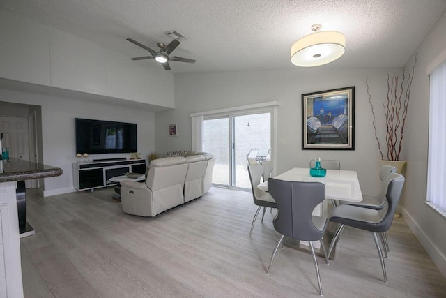 dining space with a textured ceiling, ceiling fan, vaulted ceiling, and light hardwood / wood-style flooring