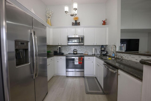 kitchen featuring decorative light fixtures, stainless steel appliances, sink, and white cabinetry