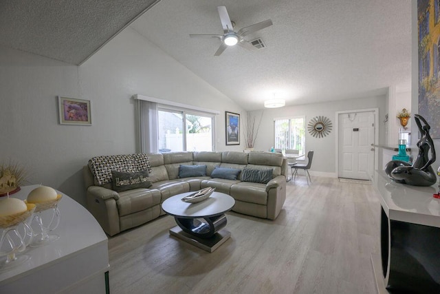 living room featuring a textured ceiling, ceiling fan, vaulted ceiling, and light hardwood / wood-style flooring