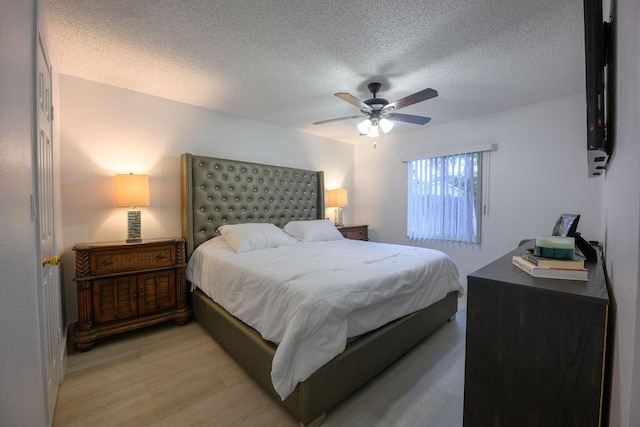 bedroom with a textured ceiling, ceiling fan, and light hardwood / wood-style flooring