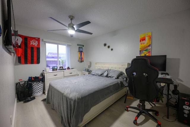 bedroom with light wood-type flooring, a textured ceiling, and ceiling fan