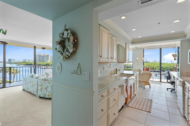 kitchen with a water view, a wealth of natural light, cream cabinetry, and light tile patterned floors