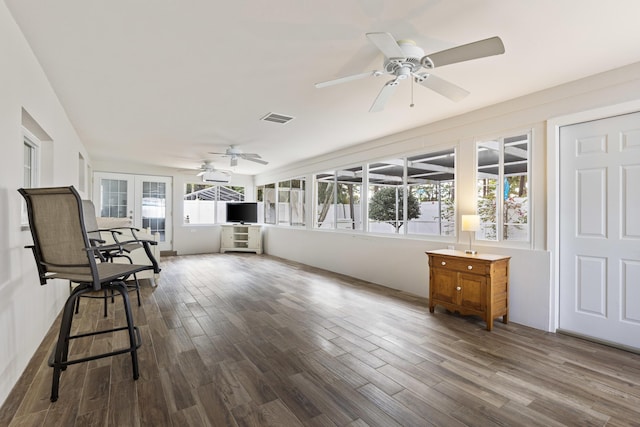 unfurnished sunroom featuring a wealth of natural light, ceiling fan, and french doors