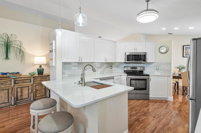 kitchen featuring kitchen peninsula, appliances with stainless steel finishes, backsplash, decorative light fixtures, and white cabinets