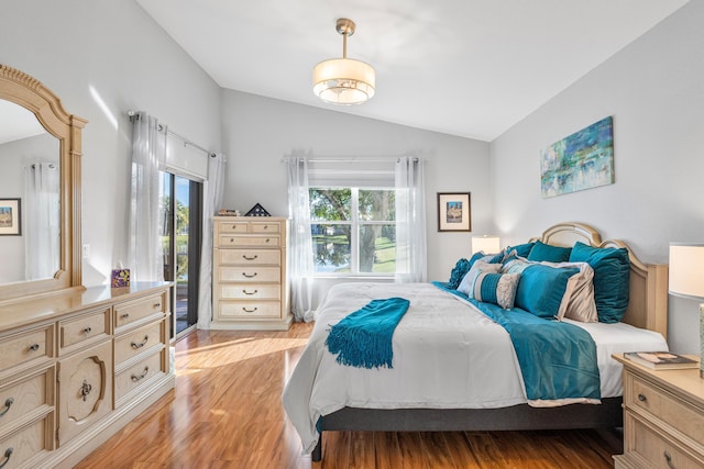 bedroom featuring lofted ceiling, light wood-style flooring, and access to outside