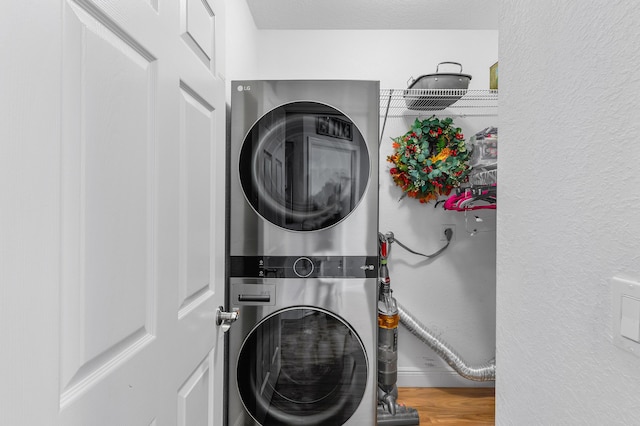 washroom with wood-type flooring and stacked washer and clothes dryer