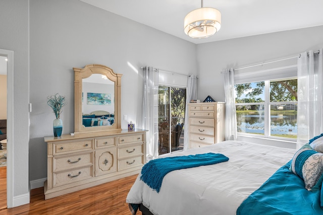 bedroom featuring multiple windows, light hardwood / wood-style flooring, and a water view