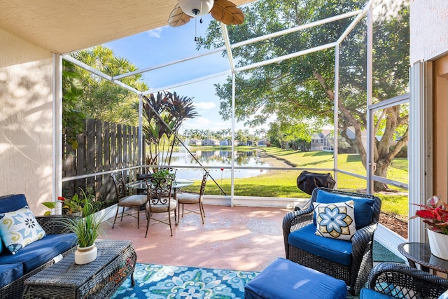 sunroom featuring ceiling fan and a water view