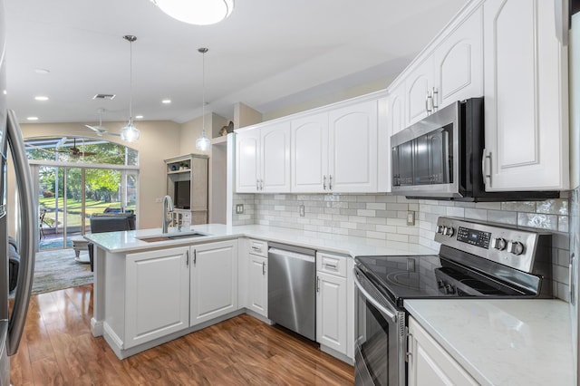 kitchen with a sink, stainless steel appliances, a peninsula, and white cabinetry