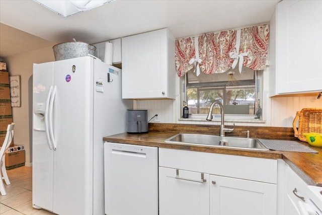 kitchen with white appliances, white cabinetry, butcher block counters, and sink