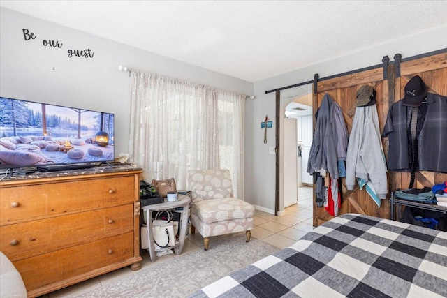 tiled bedroom featuring a barn door and a textured ceiling