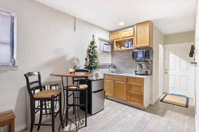 kitchen with appliances with stainless steel finishes, backsplash, light hardwood / wood-style flooring, and sink