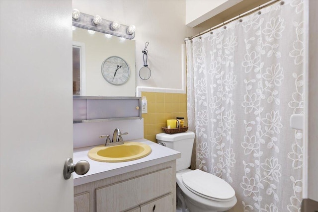 bathroom with vanity, toilet, and tile walls