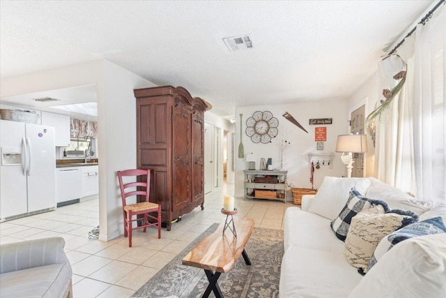 living room featuring light tile patterned floors, a textured ceiling, and sink