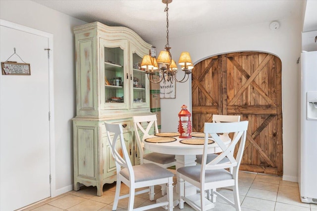 tiled dining space with a textured ceiling, a barn door, and a notable chandelier