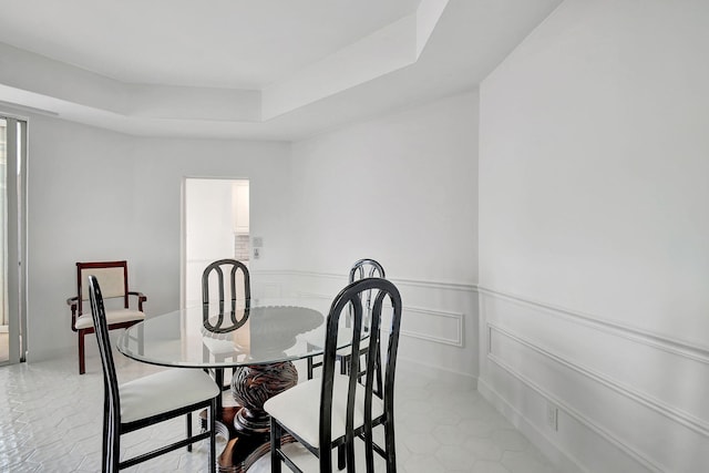 dining area featuring light tile patterned flooring and a tray ceiling