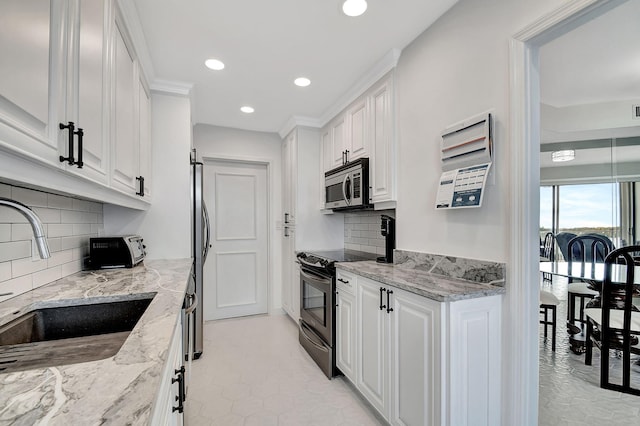 kitchen featuring sink, white cabinets, decorative backsplash, light stone counters, and stainless steel appliances