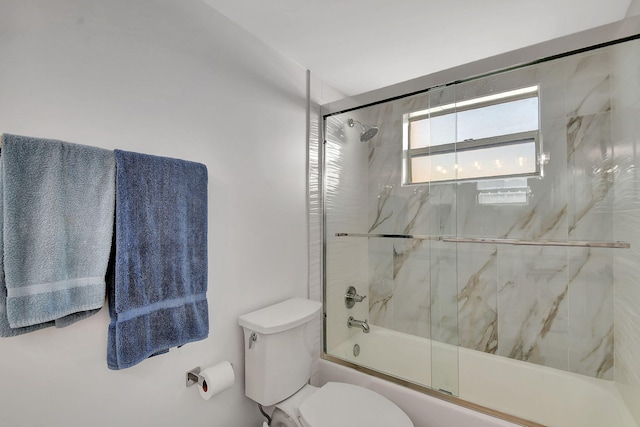 bathroom featuring bath / shower combo with glass door and toilet