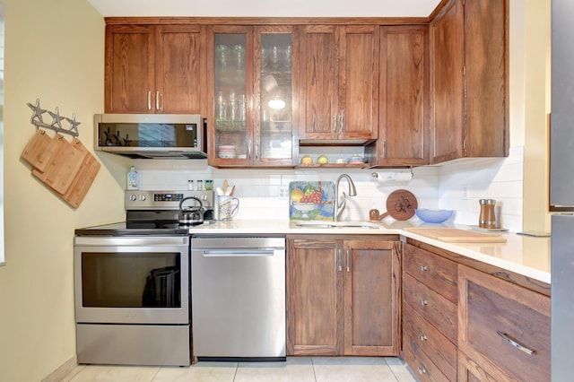 kitchen with decorative backsplash, light tile patterned floors, sink, and appliances with stainless steel finishes