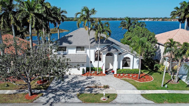 view of front facade with a garage, a water view, and a front lawn