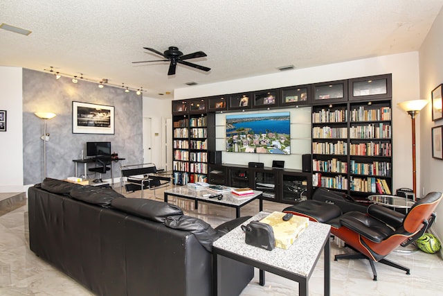 living room with ceiling fan, rail lighting, and a textured ceiling