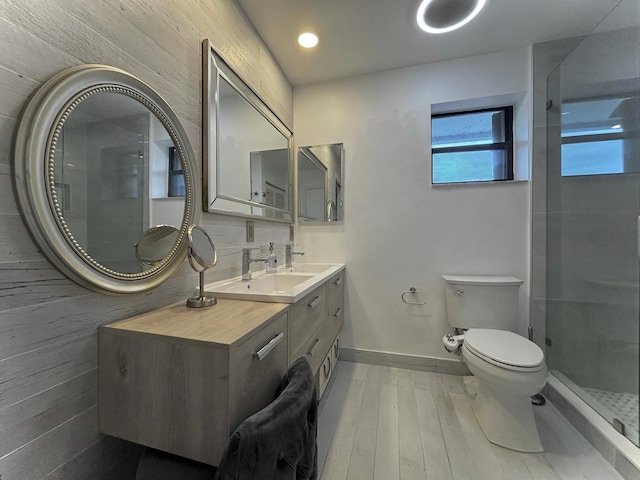 bathroom featuring a shower with door, vanity, hardwood / wood-style flooring, and toilet