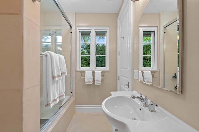 bathroom featuring a shower with door, a healthy amount of sunlight, and sink