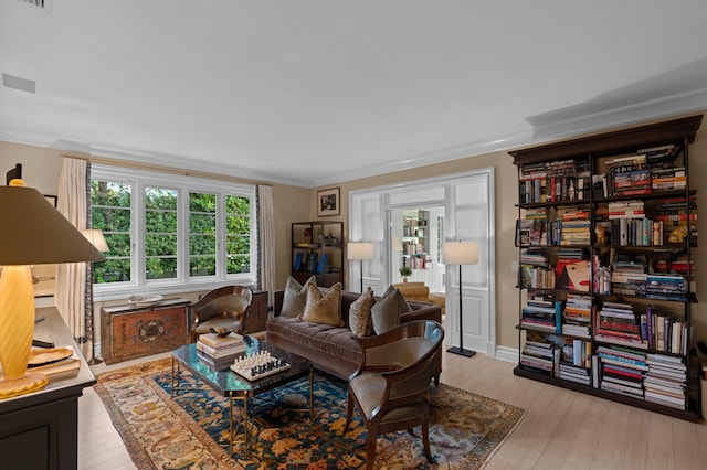 living room featuring light wood-type flooring, a wealth of natural light, and ornamental molding