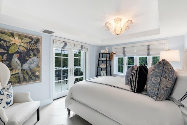 bedroom featuring access to exterior, french doors, a chandelier, and a raised ceiling