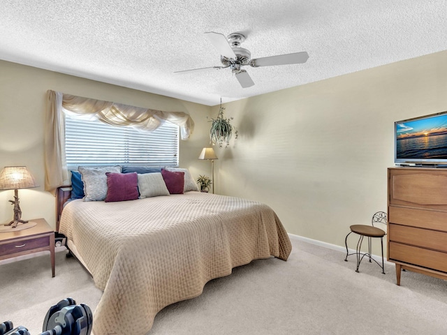 bedroom with ceiling fan, light carpet, and a textured ceiling