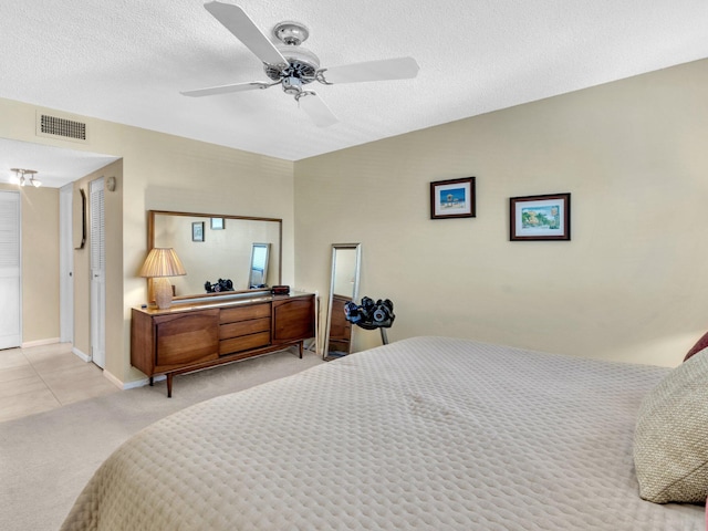 bedroom featuring ceiling fan, light colored carpet, and a textured ceiling