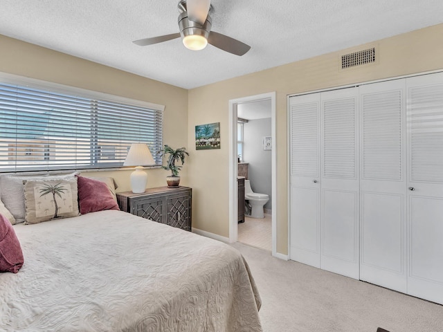 carpeted bedroom with ceiling fan, ensuite bathroom, a closet, and a textured ceiling