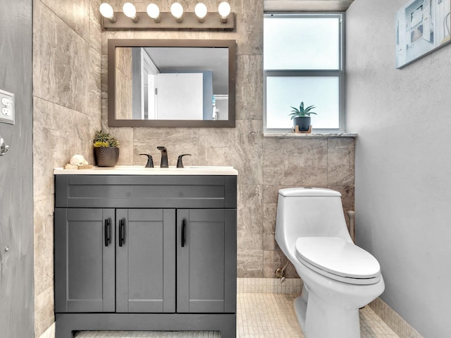 bathroom with vanity, tile patterned flooring, tile walls, and toilet