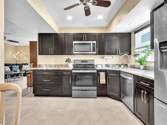 kitchen with light stone counters, stainless steel appliances, sink, and dark brown cabinets