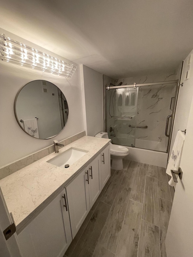 full bathroom with shower / bath combination with glass door, vanity, and toilet