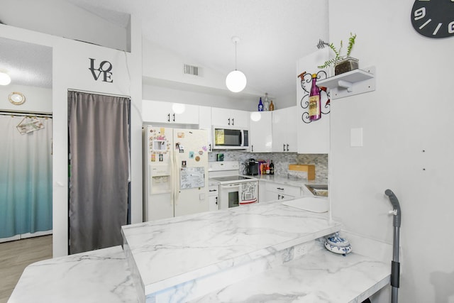 kitchen with white cabinetry, kitchen peninsula, backsplash, white appliances, and light stone counters