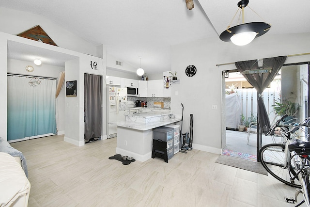 kitchen with tasteful backsplash, vaulted ceiling, white appliances, hanging light fixtures, and white cabinets