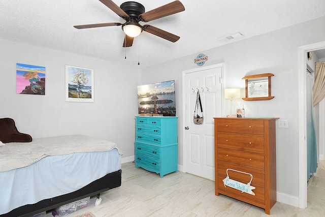 bedroom with ceiling fan and a textured ceiling