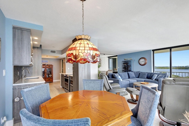 dining area featuring light wood-type flooring, a water view, and sink