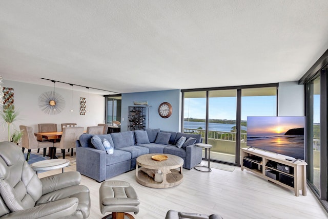 living room with a textured ceiling, a wall of windows, and light hardwood / wood-style floors