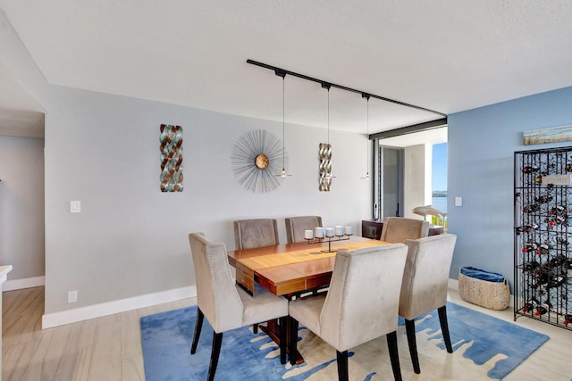 dining room with a textured ceiling, track lighting, and light hardwood / wood-style floors