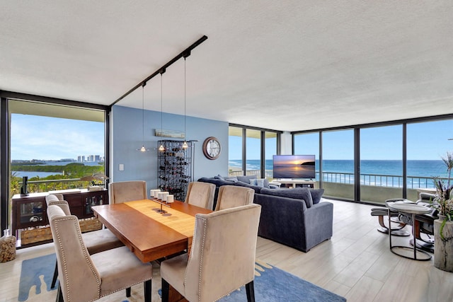 dining area with a water view, floor to ceiling windows, and a textured ceiling