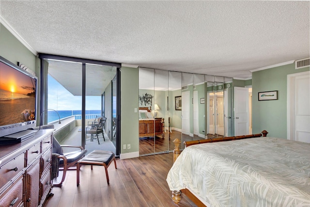 bedroom featuring a textured ceiling, ornamental molding, hardwood / wood-style floors, and access to outside