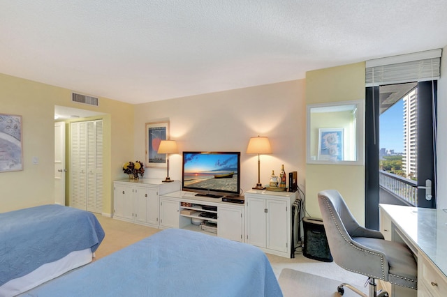 bedroom featuring light colored carpet, a closet, and a textured ceiling