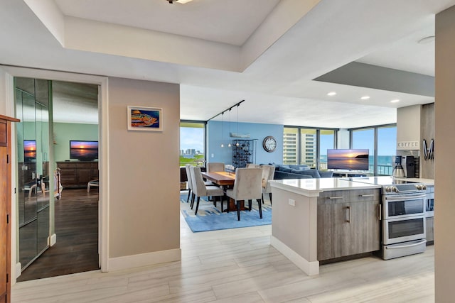 kitchen with decorative light fixtures, a wall of windows, double oven range, and a tray ceiling