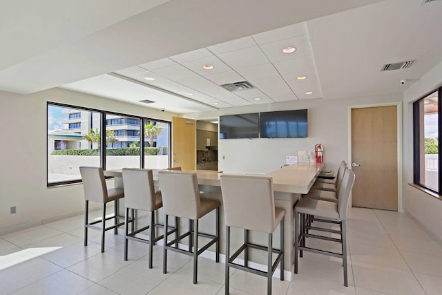 kitchen with light tile patterned floors, kitchen peninsula, and a kitchen bar