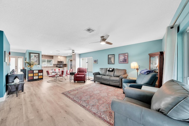 living room featuring light hardwood / wood-style floors, plenty of natural light, a textured ceiling, and ceiling fan