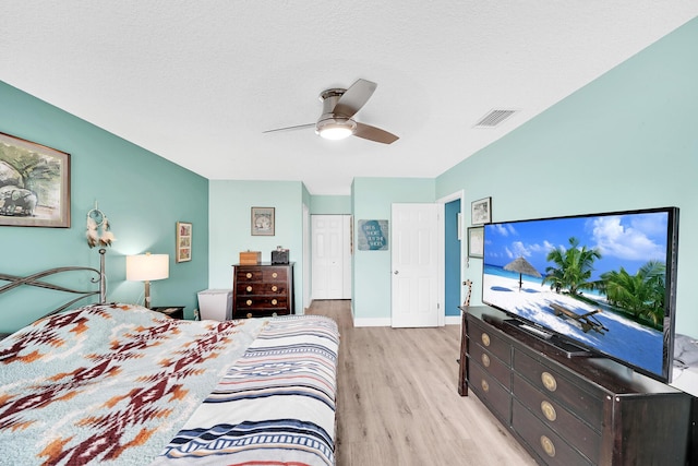 bedroom with a textured ceiling, ceiling fan, and light hardwood / wood-style flooring