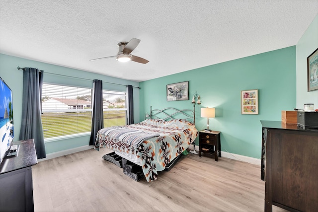 bedroom featuring ceiling fan, a textured ceiling, and light wood-type flooring