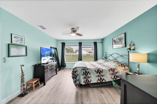 bedroom with ceiling fan, a textured ceiling, and light hardwood / wood-style flooring